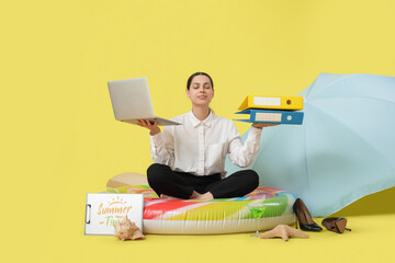 Wall Mural - Female office worker meditating on inflatable ring with laptop on yellow background. Summer vacation concept