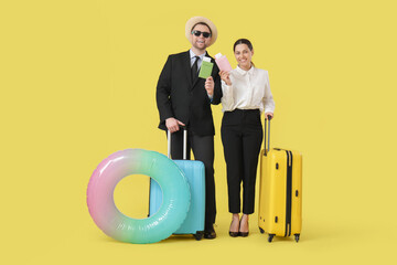 Wall Mural - Happy office workers in sunglasses with passport and suitcases on yellow background. Summer vacation concept