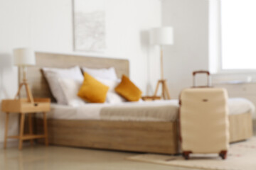 Poster - Blurred view of modern hotel room with suitcase near bed