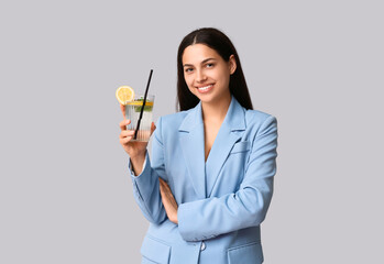 Poster - Beautiful young happy woman with glass of fresh lemonade on grey background