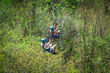 © Brocreative - A couple riding a zipline in Costa Rica while on vacation. View from behind as the tourists zip down a jungle mountain on an adventure tour.