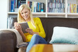 © peopleimages.com - Woman, relax and happy on sofa with tablet for internet surfing, online search or social media in living room of home. Person, smile and digital tech for reading ebook, web games or browsing on couch