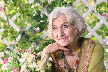 Wall Mural - Beautiful elderly woman sits at a table in the summer at the country house