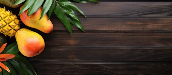 Tropical fruits like mango and papaya displayed on a wooden background in a top view setting with copy space for text or images