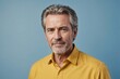 © ThomasLENNE - Portrait of charming mature man true boss feel content emotions wear yellow shirt isolated over blue color background
