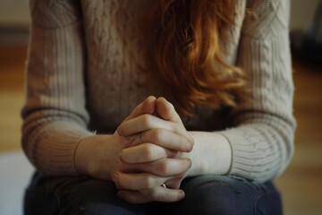 A young woman clasped hands indicative of her nervousness as she sits in a therapy session