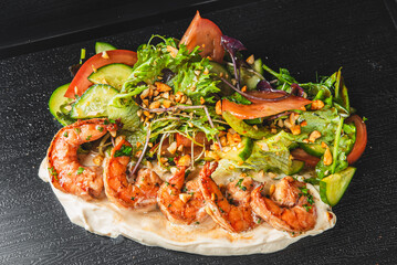 Wall Mural - Colorful shrimp salad with mixed greens, tomatoes, cucumbers, and nuts on a dark surface