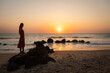 © Milou Dirks - silhouette of woman at sunset standing in dress on rocks in the water on beach and ocean