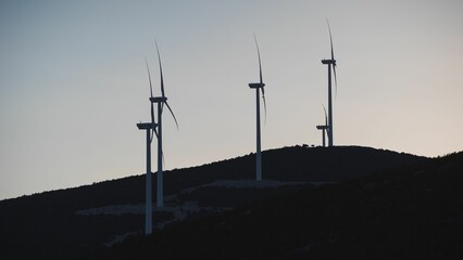 Wall Mural - Wind turbines on top of a mountain against a scenic sunset
