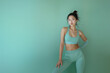 © NaphakStudio - Chic Korean fitness model in minimalist green athletic gear, standing against a matching green background. Her stylish pose and the cohesive color scheme highlight elegance and fitness.