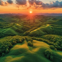 Summer nature scenery at sunset with green forests and meadow and blue sky Panoramic aerial view on hills with orange sun shining above horizon with copy space Please provide high-resolution