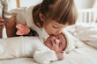 © ADDICTIVE STOCK - Toddler sister giving a gentle kiss to her sleeping newborn brother