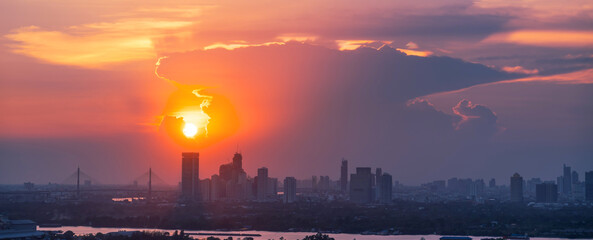 Wall Mural - Sunrise over modern office buildings in district center of Bangkok. Panoramic skyline view of cityscape with sunlight and flare in warm light color tone. Construction business concept.