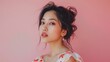 © Wattana - An enchanting beauty portrait showcases the grace and sophistication of a young Asian woman, her delicate features and elegant dress accentuated by the pink background.