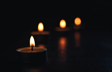 Wall Mural - Small Candles Burning on a Black Background, Symbolizing Reflection and Remembrance on Memorial Day