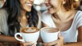 Two young women are sitting in a cafe and drinking coffee. They are both smiling and laughing and seem to be enjoying their conversation.