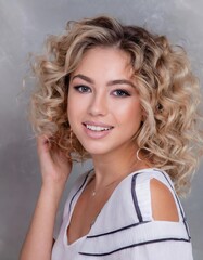 Wall Mural - Blonde woman with curly beautiful hair smiling on gray background