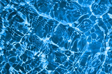 blue and bright water in swimming pool with sun reflection