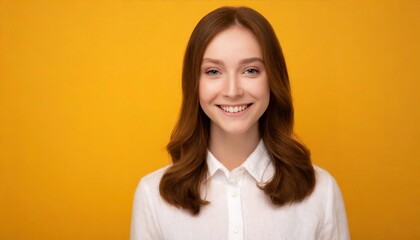 Portrait of a cheerful young woman wearing white shirt standing isolated over yellow background, looking at camera, posing