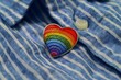 © Picasso - A rainbow heart shaped enamel pin resting on a blue shirt