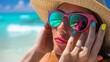 © Chiradet - Woman with a colorful nail polish manicure, adjusting her stylish sunglasses on the beach