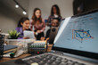 © qunica.com - A group of young professionals discusses a project around a laptop in a well-equipped, modern office setting, highlighting teamwork and collaboration.