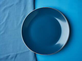 Wall Mural - Round blue plate rests on a colorful tablecloth in top view