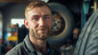 © Anthichada - Close up smiling face auto mechanic caucasian man in uniform looking to camera standing at tire shop or car repair station. Auto service, repair, maintenance concept