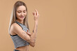© New Africa - Tattooed woman applying cream onto her arm on beige background, space for text