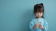 © Katsiaryna - The little girl in the blue dress is staring at a cellphone, copy space