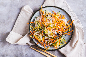 Wall Mural - Close up of appetizing salad of funchose, carrots, cucumber and sesame on a plate  top view