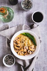 Wall Mural - Asian soup with rice noodles, mushrooms and green onions in a bowl top and vertical view