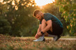 © Malik Nalik - A young athletic man tying running shoes with wireless earphones listening a music for motivation preparing for a run or workout at the park active lifestyle.