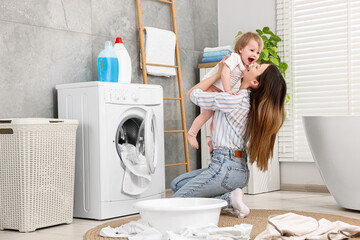 Canvas Print - Mother with her daughter having fun while washing baby clothes in bathroom