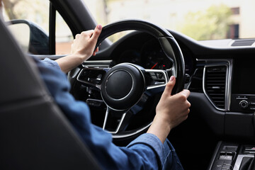 Wall Mural - Woman holding steering wheel while driving her car, closeup