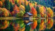 © prasit - A secluded cabin nestled among tall trees beside a tranquil lake, surrounded by the vibrant colors of autumn