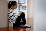 Fototapeta  - A girl is sitting on the floor reading a book