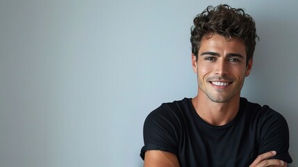 Wall Mural - smiling handsome man in a casual black t-shirt with arms crossed