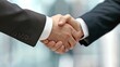 © sunthon - Close-up of two business professionals shaking hands, symbolizing a successful partnership or agreement in an office setting.