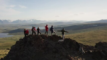 Aufkleber - Big group of diverse tourists or hikers are standing on mountain top with great view at valley with sunset lakes and snowy mountains. Drone flights around peoples on big rock
