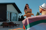 Fototapeta  - Woman in a bikini carrying a food tray to a man in their holiday home