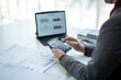 © Wasana - A man is sitting at a desk with a calculator and a laptop