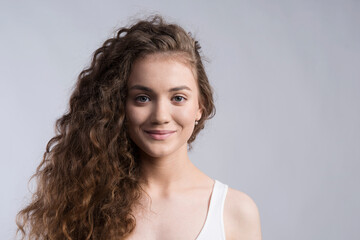 Canvas Print - Portrait of a gorgeous teenage girl with curly hair. Studio shot, white background with copy space