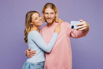 Wall Mural - Young couple two friends family man woman wear pink blue casual clothes together do selfie shot on mobile cell phone post photo on social network hug cuddle isolated on plain light purple background.