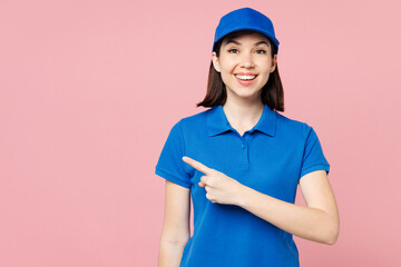 Sticker - Professional fun delivery girl employee woman wear blue cap t-shirt uniform workwear work as dealer courier point index finger aside on area isolated on plain pink background studio. Service concept.