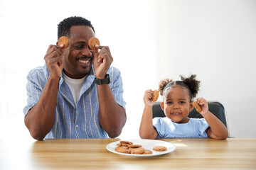 portrait father and daughter showing chocolate cookies on the table