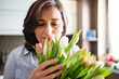 © Halfpoint - Portrait of beautiful mature woman with black hair and soft smile, holding bouquet of tulips.