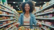 © YURIMA - A happy woman with curly hair enjoys grocery shopping in a brightly lit supermarket aisle. She smiles as she pushes a cart filled with fresh produce, embodying a cheerful and healthy lifestyle