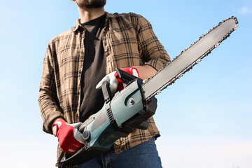 Wall Mural - Man with modern saw against blue sky, closeup