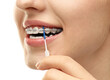 © New Africa - Woman with dental braces cleaning teeth using interdental brush on white background, closeup